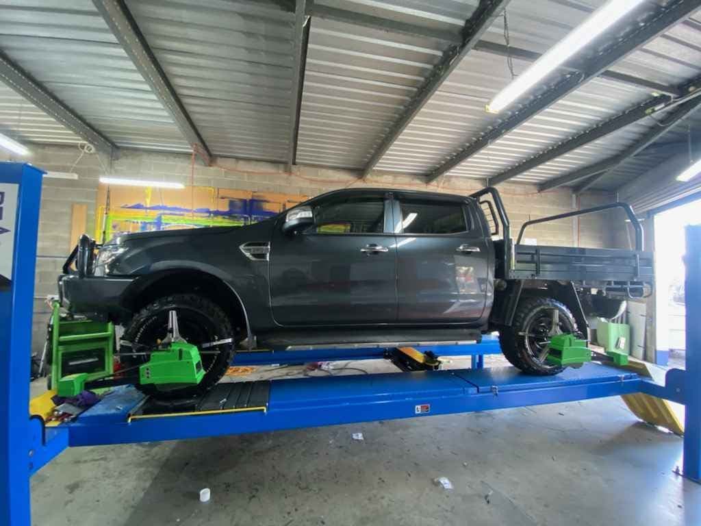 Picture Of A Black Car Receiving A Wheel Alignment Service